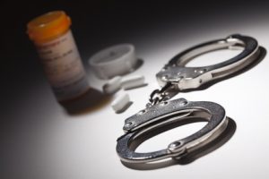 Handcuffs, Medicine Bottle and Pills Under Spot Light